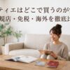 タブレットで購入先を調べる女性と、カードや旅行書類が置かれたテーブル