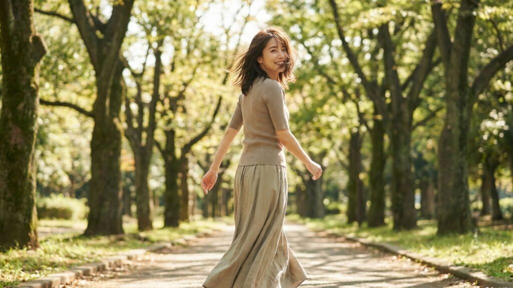緑の多い公園を歩きながら振り返るカジュアルな服装の女性